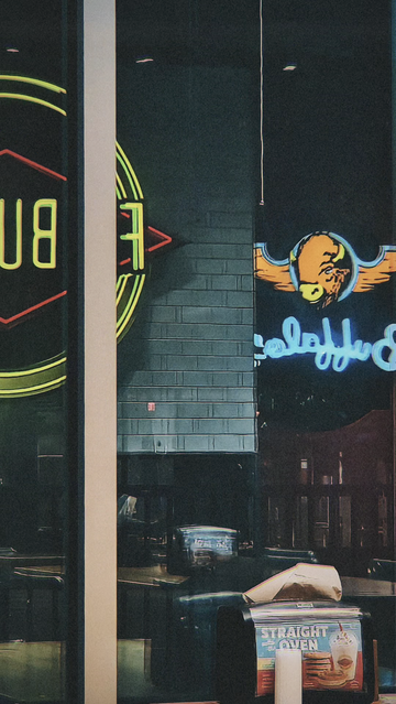 Reflections of several neon fast food logos in the window of a 'Fatburger & Buffalo's Express' in Los Angeles.